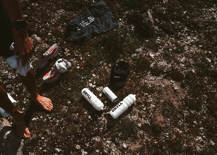 DRYLL Essentials nach dem Sport. Trinkflaschen, die Running Cap und das Elektrolytgetränk in Benutzung.