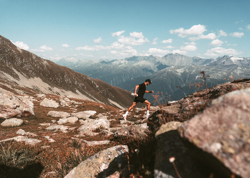 Ein DRYLL Trail Runner in den schweizer Alpen. Mit DRYLL Trinkflasche 500ml in der Hand.