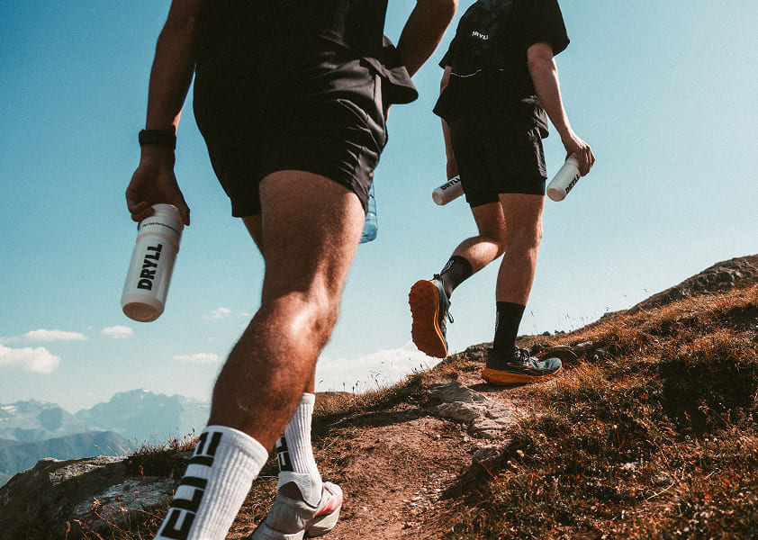 DRYLL Trinkflasche in der Hand eines Ultra Runners auf dem Weg zum Berggipfel.
